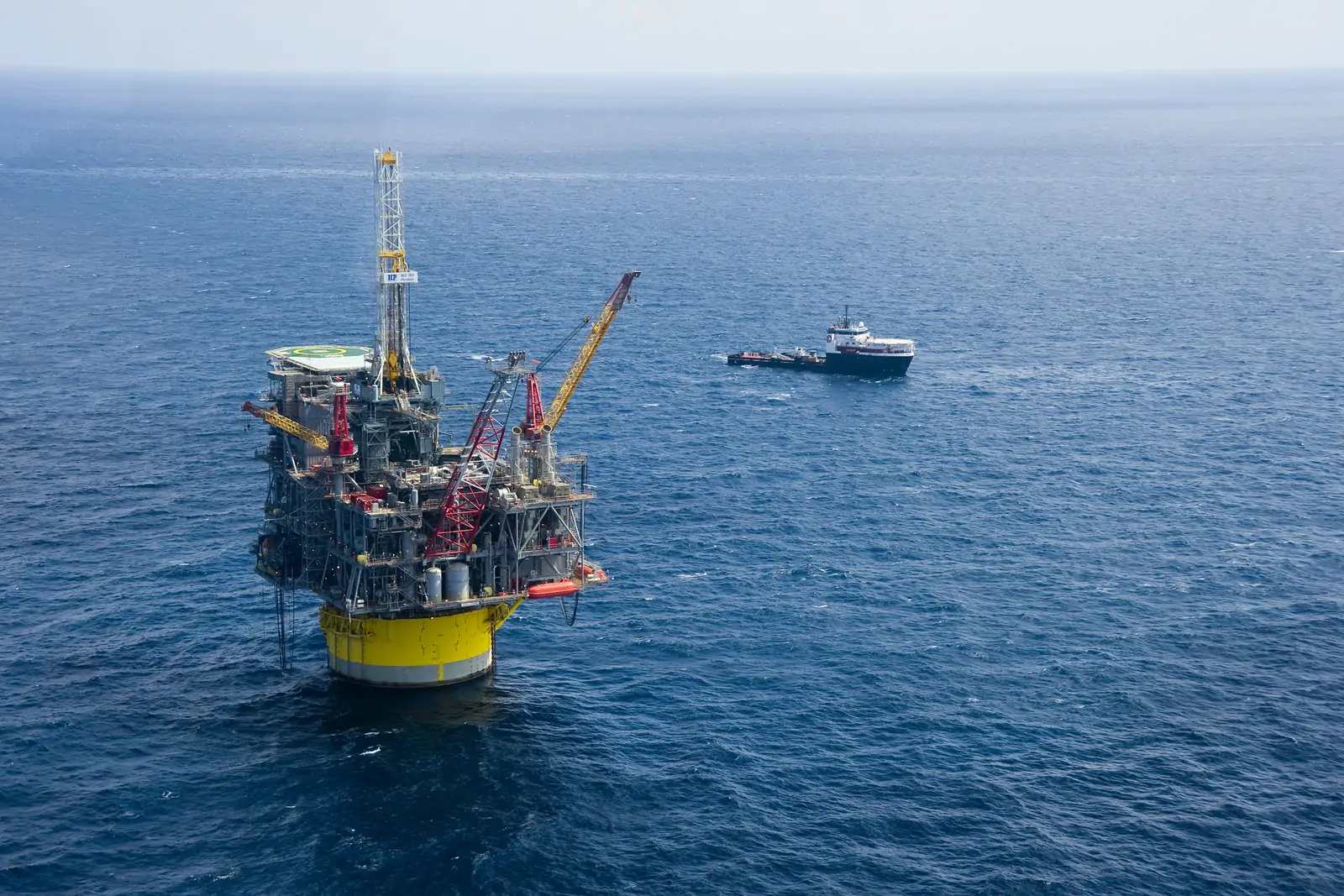 A deepwater production platform on station in open water with an offshore supply vessel standing by.